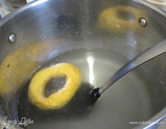 В кастрюле вскипятить воду с пищевой содой. Выложить поочередно бублики (можно по 2 — 3 шт.), проваривать по 30 — 40 секунд.