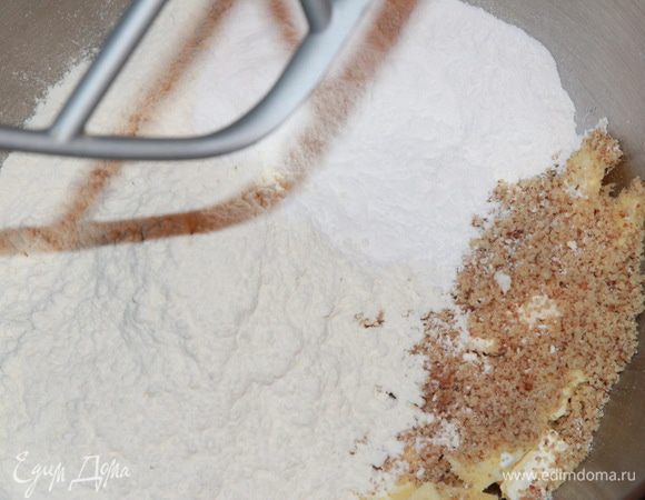 Сначала приготовим основу из теста сабле, на которой будет стоять наш торт. Для этого в чашу комбайна кладем нарезанное кубиком масло, затем добавляем молотые в очень мелкую крошку орехи, соль, сахарную пудру и муку. 