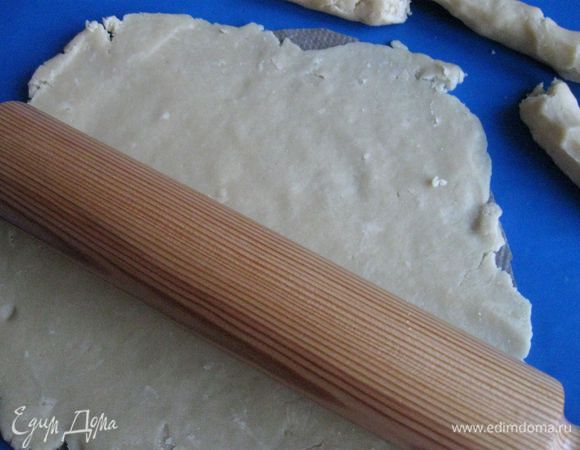 Достать тесто из холодильника. Отделить часть теста для бортиков. Основу я раскатываю на бумаге для выпечки, вырезанной по размеру дна формы, тесто вместе с бумагой потом кладу на дно формы.