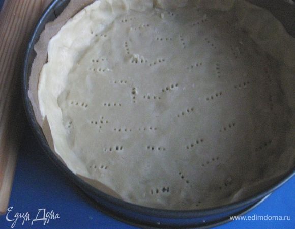 Борта формы также закрыть бумагой для выпечки. Сформировать бортики из теста. Основу из теста наколоть вилкой. Убрать основу в холодильник на 10 — 15 минут.
