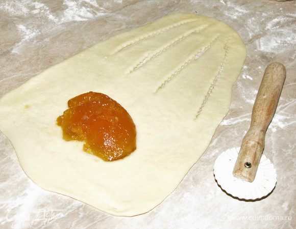 Затем раскатать каждый шарик в овал, одну половину овала сделать шире. Смотрите, как на фото. С узкого края сделать четыре прорези с помощью кулинарного колесика или ножа. Выложить начинку на широкий край.