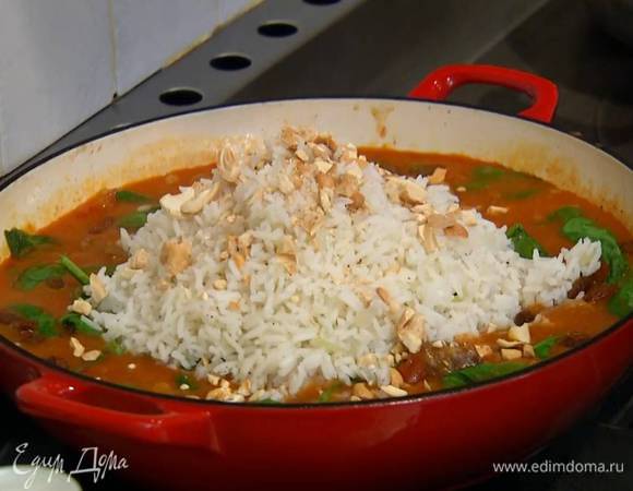 Мясо с овощами посыпать изюмом, выложить в центр сковороды готовый рис и посыпать все орехами.