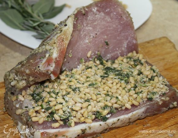 Сделайте на мясе глубокий продольный разрез, раскройте, как книгу. Для начинки измельчите чеснок, листики шалфея и листики с одной веточки розмарина, добавьте соль и перец, натертый сыр и масло, в котором мариновалось мясо. Соедините ароматные травы с кедровыми орешками, при желании орешки можно измельчить. Выложите начинку в разрез..