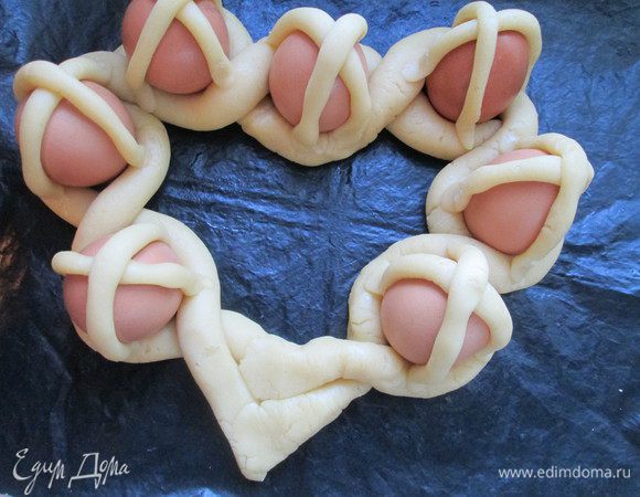 Укладываем на каждое яйцо жгутики крестообразно, прикрепляя их к основным жгутам. Руки смачиваем постоянно, чтобы детали из теста крепче соединялись.