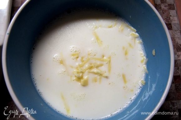 Молоко нагреть примерно до 60°С. Сыр натереть. Половину сыра положить в молоко, туда же добавить муку и хорошо размешать.