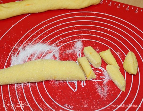 Скатать 2 колбаски толщиной 4 см. Высыпать остатки сахара и обвалять в нем колбаски. Острым ножом нарезать колбаску на диски толщиной 0,7 — 1 см.