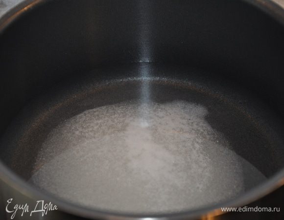 В первую очередь необходимо замариновать лук. Для этого налейте в кастрюлю стакан воды, добавьте 3 столовые ложки сахара и половину столовой ложки соли.