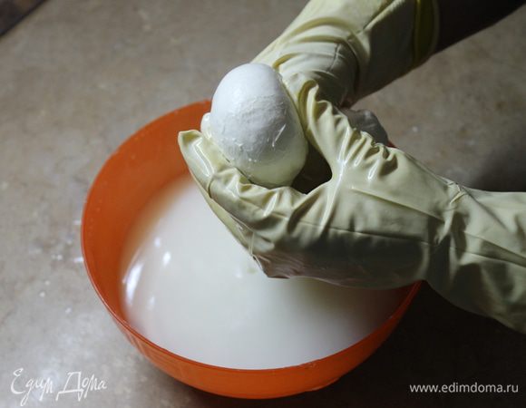 Растягиваете сырную массу, формируете шарик, подворачивая края внутрь шарика, выдавливаете его между большим и указательным пальцами, отрезаете получившуюся моцареллу.