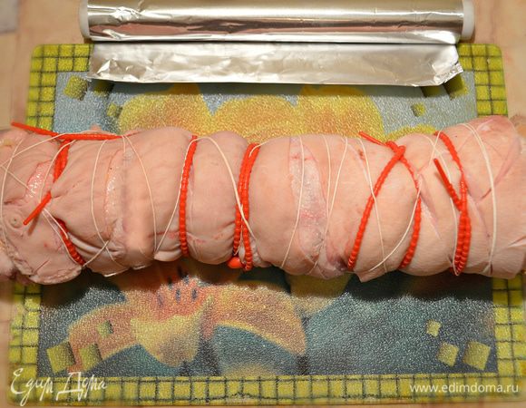 Сверните кусок мяса в плотный рулет. Затем свяжите рулет кулинарной нитью, жгутами, зафиксировав его форму.
