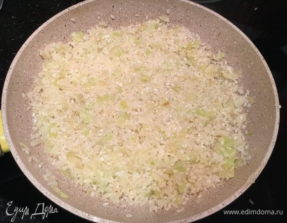 Добавьте рис и увеличьте огонь до максимума. Готовьте 1 минуту, все время помешивая, он станет немного прозрачным. Влейте вермут и продолжайте помешивать.