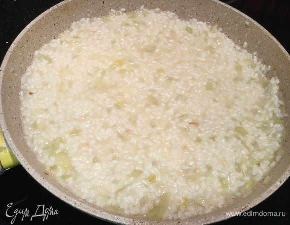 Как только пропадет резкий алкогольный запах, и вермут частично выпарится, а частично впитается в рис, добавьте половник бульона и щепотку соли. Убавьте огонь. Продолжайте готовить, постепенно по половнику добавляя бульон, постоянно перемешивая рис. Этот процесс займет около 15 минут. Добавляя новый половник бульона, убедитесь, что предыдущий полностью впитался в рис. Рис должен стать мягким, но при этом не превратиться в кашу.