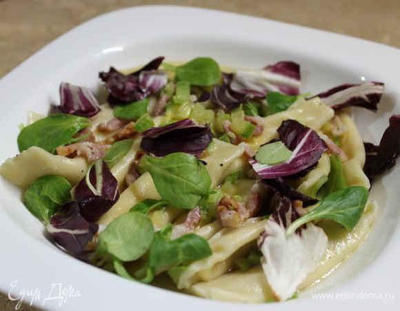 Подогрейте тарелку, выложите равиоли, разложите сверху листики салата и хлопья пекорино.