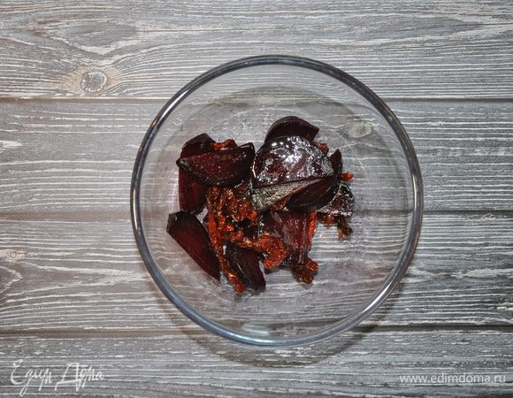 Свеклу сначала разрежьте пополам, а затем нарежьте небольшими дольками. Положите томаты (вместе с небольшим количеством масла) и свеклу в салатник и перемешайте.