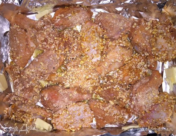 Берем полиэтиленовый пакет и высыпаем туда нашу панировку. По три-четыре кусочка курицы слегка обмакиваем в мисочку с растопленным маслом и кладем в пакет, закручиваем его, чтобы получился пузырь, и трясем. Достаем курицу, выкладываем в форму. Повторяем до тех пор, пока не обваляем все кусочки. Я по бокам добавила еще несколько кусков сливочного масла, но это я просто маловато в форму налила изначально. Ставим в духовку.