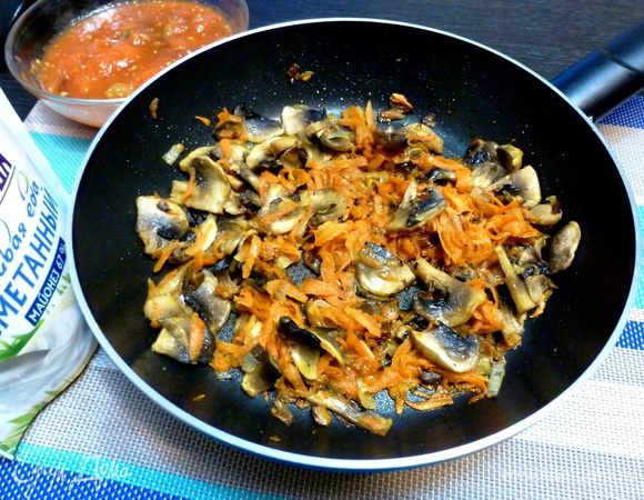 Готовим подливу для тефтелей. Поджарим лук и морковь до мягкости. Шампиньоны нарежем пластинками и добавим к овощам. Обжариваем все вместе минут 5.