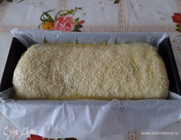 Выкладываем рулет в форму для выпечки. Смазываем яичным желтком и посыпаем кунжутом. Накрываем форму полотенцем и оставляем на 20 минут.
