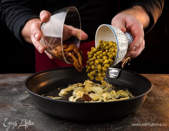 На оливковом масле обжарить лук, затем добавить мелко нарезанный чеснок, слегка обжарить его. Добавить опята и горошек, готовить 5 — 7 минут.
