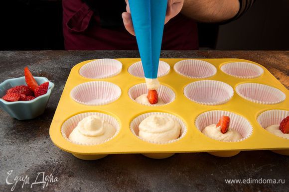 Выложить тесто в формочки на 1/3, положить пару ягод клубники, сверху прикрыть тестом.