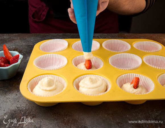 Выложить тесто в формочки на 1/3, положить пару ягод клубники, сверху прикрыть тестом.