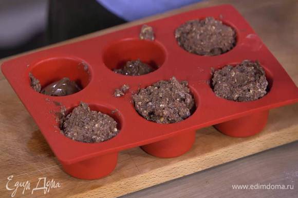 Формочки для маффинов заполнить тестом на 1/3 объема, затем добавить в каждую по 1 ч. ложке шоколадно-ореховой пасты, сверху выложить оставшееся тесто.