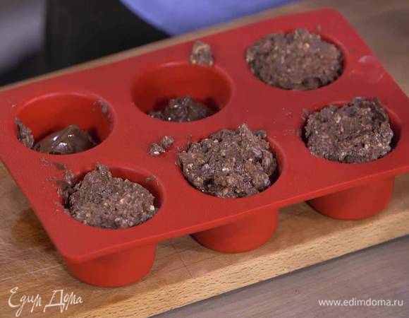 Формочки для маффинов заполнить тестом на 1/3 объема, затем добавить в каждую по 1 ч. ложке шоколадно-ореховой пасты, сверху выложить оставшееся тесто.