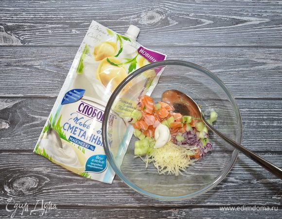 Приготовьте салат для тарталеток: в отдельную посуду положите огурцы, семгу, лук и пармезан, заправьте майонезом ТМ «Слобода» Сметанный и перемешайте.