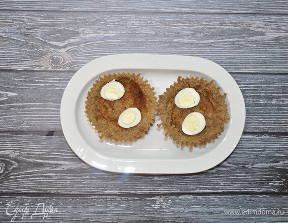 Перепелиные яйца заранее отварите, разрежьте пополам и уложите на дно тарталеток.