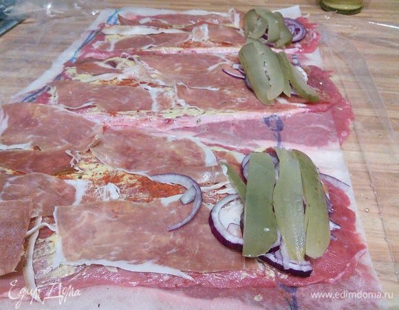 Выложить немного лука, нарезанного полукольцами, и слайсы огурца (подойдет соленый, маринованный, на ваш вкус). 