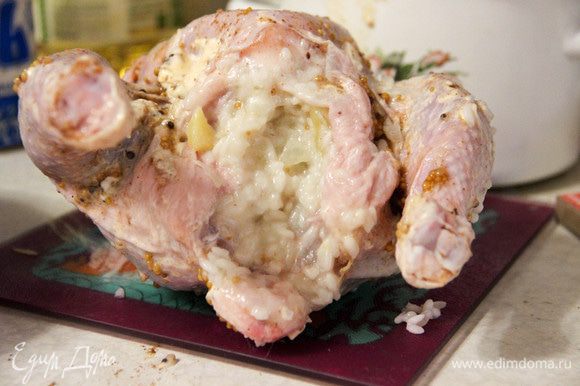 Цыпленка аккуратно начинить рисом. Зубочистками или ниткой закрепить кожу, чтобы начинка не вываливалась. Отправить цыпленка в разогретую до 200°С духовку на 30 минут. Затем уменьшить температуру и перевернуть тушку. Запекать еще полчаса.