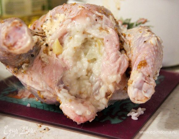 Цыпленка аккуратно начинить рисом. Зубочистками или ниткой закрепить кожу, чтобы начинка не вываливалась. Отправить цыпленка в разогретую до 200°С духовку на 30 минут. Затем уменьшить температуру и перевернуть тушку. Запекать еще полчаса.