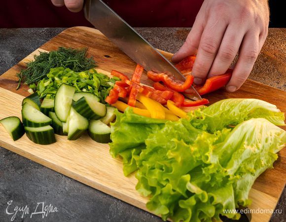 Огурец и разноцветный болгарский перец нарезать кубиками. Салат нашинковать. Измельчить зелень.