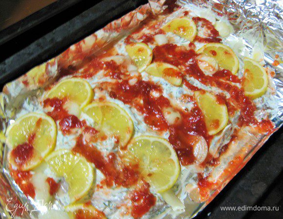 Сверху выкладываем дольки лимона, лук полукольцами, протертые помидоры в собственном соку. Запекаем в духовке 25 минут.