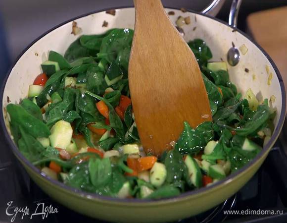 Перец чили вместе с семенами тонко порезать, выложить к овощам, посыпать тмином и еще немного обжарить, затем добавить шпинат и дать ему поплыть.