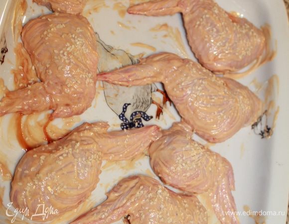 Нафаршировать крылышки, на концах кожицу завернуть. Разложить на листе, смазанном растительным маслом. Смазать майонезом и кетчупом, посыпать кунжутом.