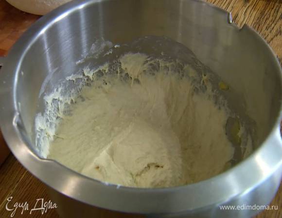 В чашу комбайна всыпать оставшуюся муку, влить 100 мл теплой воды, 1 ст. ложку оливкового масла, медово-дрожжевую смесь и вымешать все на медленной скорости, затем, не выключая комбайна, добавить соль, влить еще 130 мл теплой воды и вымешивать тесто 10 минут.