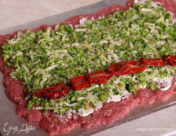 Сверху выкладываем начинку, и с того края, с которого будем скручивать рулет, выкладываем полоской вяленые помидоры