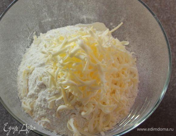 Просеять муку в миску. Натереть на терке сливочное масло, заранее сильно охлажденное.