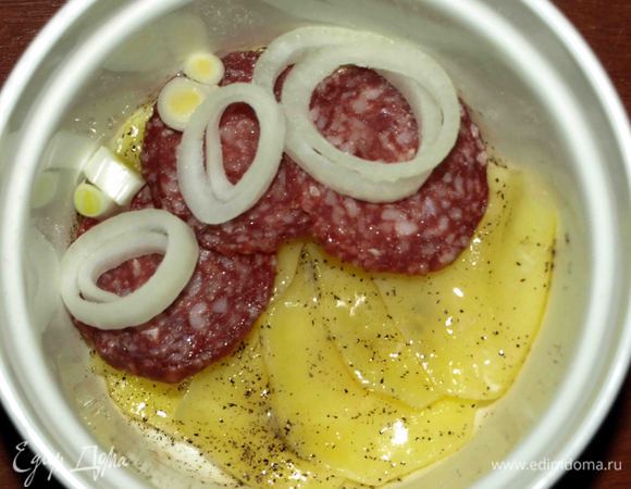 В порционные формочки выкладываем первый слой картофеля, солим, перчим и смазываем растопленным сливочным маслом. Сверху выкладываем лук и салями.