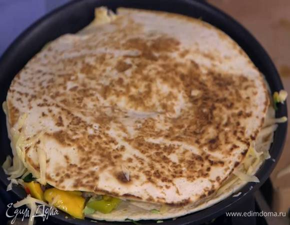 Одну тортилью прогреть на сухой сковороде, выложить на нее половину натертого сыра, фарш, маринованный перец, авокадо и соус из манго, посыпать оставшимся сыром, накрыть второй тортильей, перевернуть и прогревать все еще минуту.