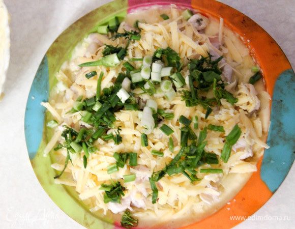 Начинку выкладываем на тесто, слегка отступив от краев. Покрываем ее сметанным майонезом. Натираем сыр, нарезаем зелень. Посыпаем поверх начинки. Выливаем оставшееся тесто. Запекать курник будем примерно 45 минут при температуре 180°С. Когда верхний слой пирога слегка подрумянится, украсим его кунжутом и смажем желтком.