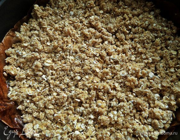 Дно формы диаметром 18 см застелить пергаментом, смазанным маслом. Насыпать слой крошки 2/3 от массы. Слегка утрамбовать.