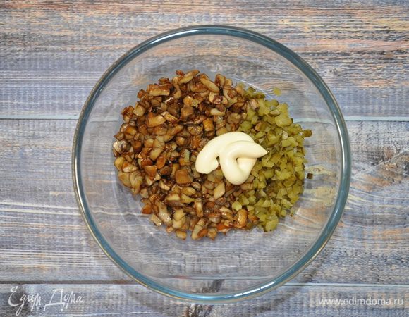 Выложите в салатник жареные грибы (грибам надо дать немного остыть до этого), лук, корнишоны, нарезанные мелкими кубиками, чуть-чуть посолите и заправьте майонезом ТМ «Слобода» Постный. Начинка для каннеллони готова.