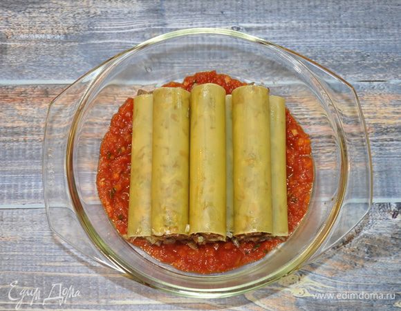 На дно формы для запекания выложите соус, на него выложите каннеллони, заправленные нашей начинкой. Начинку стоит накладывать чайной ложкой и слегка утрамбовывать ее другим концом ложки, закрывая при это пальцами другой край каннеллони, чтобы не потерять начинку.