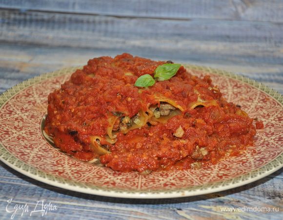 По прошествии отведенного времени достаньте блюдо из духовки и дайте ему постоять под закрытой крышкой 10 — 15 минут. Затем выложите каннеллони вместе соусом на сервировочное блюдо при помощи большой лопатки и украсьте веточкой свежего базилика.
Приятного аппетита!