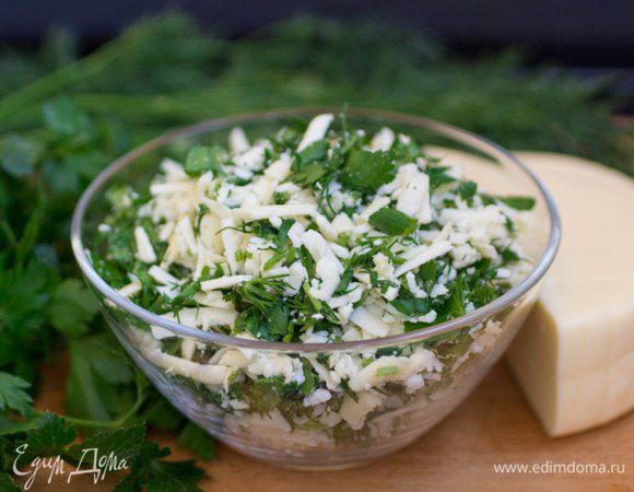 Приготовить начинку. Сыр натереть на крупной терке, зелень промыть, обсушить, отделить от стеблей и нарубить. Чеснок нарубить мелко. Все перемешать. Если сыр недостаточно соленый, приправить начинку солью по вкусу.