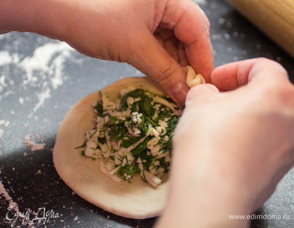 Разделить тесто на небольшие шарики. Из этого количества теста получается 8 штук. Каждый шарик раскатать в лепешку, положить по центру начинку и собрать края теста по кругу. Должен получиться небольшой колобок. Перевернуть швом вниз и оставить на 10 минут.