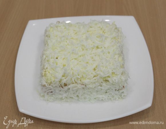 Снять кольцо и аккуратно намазать бока салата, украсить натертым белком и плавленным сыром.