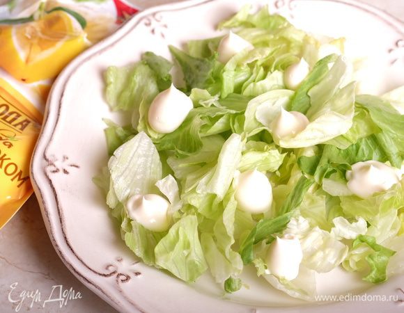 Собираем салат. На тарелку выкладываем щедрую горсть салата айсберг. Сверху — немного майонеза «Слобода» с лимонным соком.