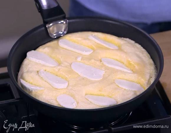 Разогреть в сковороде сливочное масло, выложить яичную массу, разровнять ее, сверху поместить ломтики козьего сыра и накрыть сковороду крышкой.