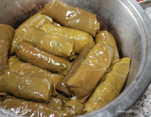 Завернуть фарш в листья винограда. Выложить в казан, залить подсоленной водой, смешанной с майонезом ТМ «Слобода» с лимонным соком, чтобы листья покрыло на 1 — 2 см, накрыть крышкой и тушить около часа. Подавать горячим.